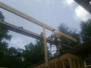 Carpenter setting a ridge beam over a new addition frame — Ice Dam Removal by Roofing Brothers in Wetmore