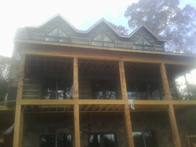 Dormers and porch framing on a large log home under construction — Roof Coating work by our crew in Wetmore