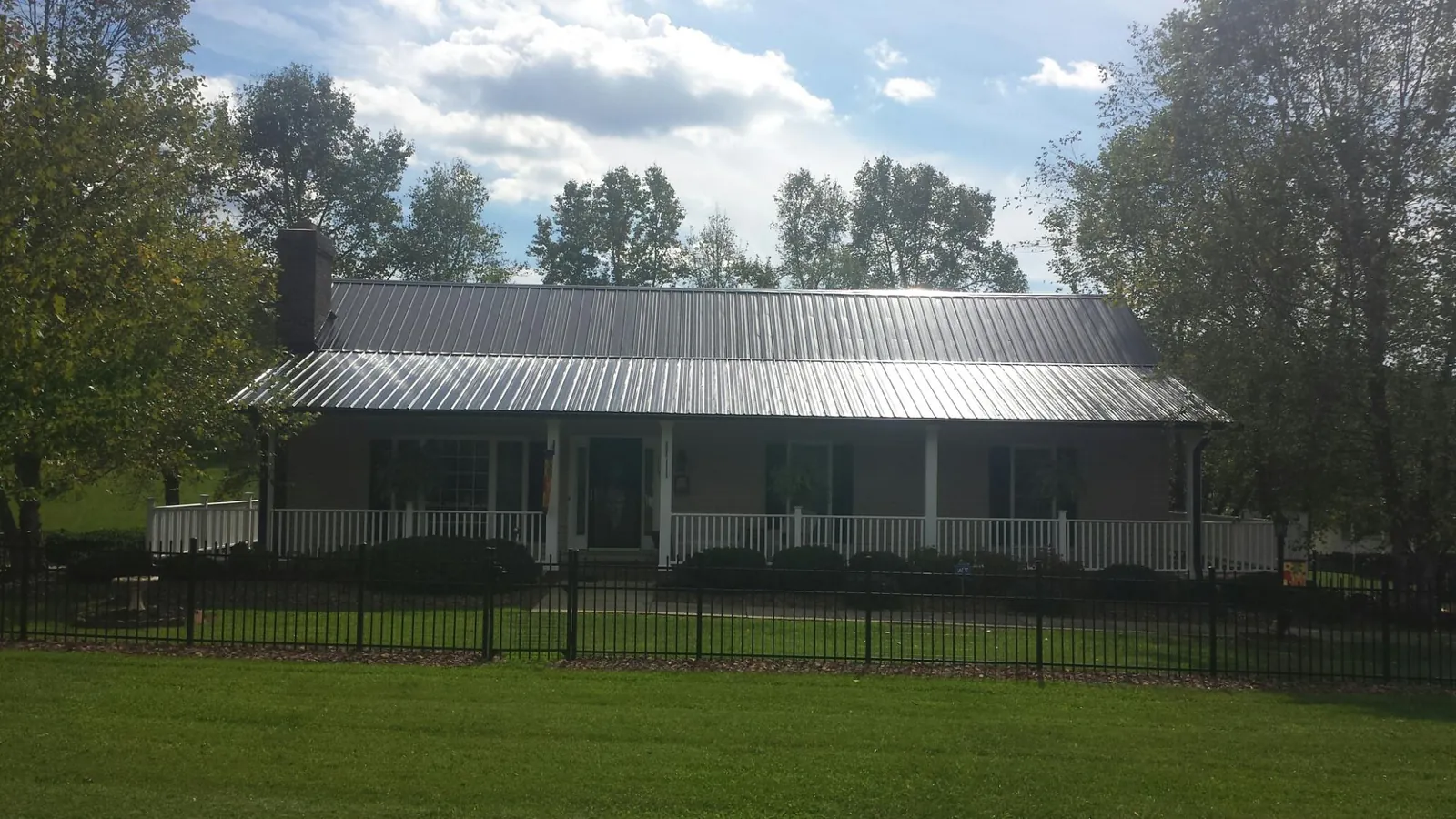 Gray metal roof on a brick ranch with a full width front porch — Gutter Guard Installation work by our crew in Wetmore