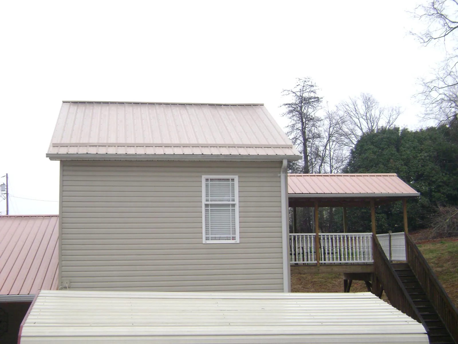 Tan metal roofs on a two story addition and attached porch, from a Roof Replacement job in Wetmore