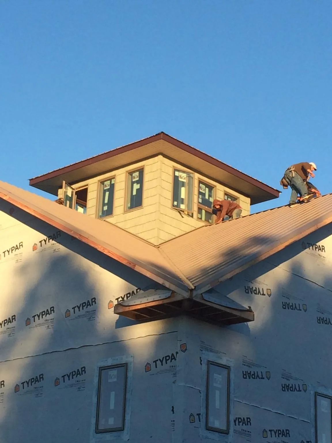 Roofers working around a rooftop cupola on a new metal roof at sunset — Roof Waterproofing in Wetmore by Roofing Brothers